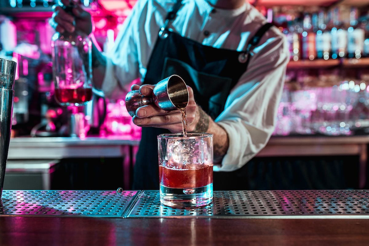 Expert barman is making cocktail at night club.